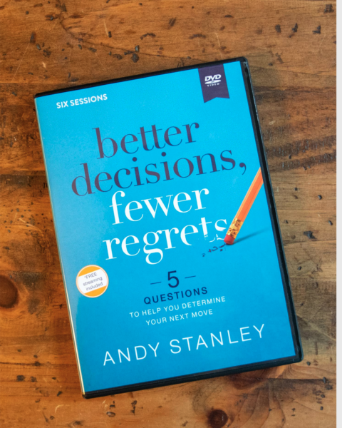 DVD case of "Better Decisions, Fewer Regrets" by Andy Stanley on wooden surface, bright blue cover with pencil graphic and subtitle "5 Questions to Help You Determine Your Next Move."