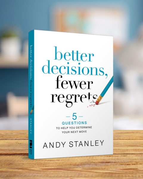 Book cover of "Better Decisions, Fewer Regrets" by Andy Stanley on blurred background, white and blue cover with pencil graphic.