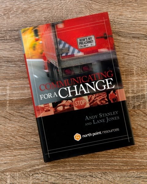 Book cover of "Communicating for a Change" by Andy Stanley and Lane Jones on wooden surface, featuring red and black design with truck/transportation imagery and "North Point Resources" publisher logo.