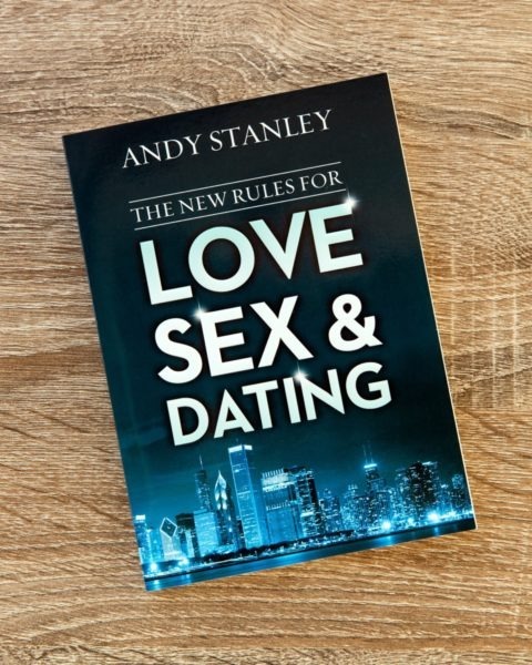 Book cover of "The New Rules for Love, Sex &amp; Dating" by Andy Stanley on wooden surface, featuring dark background with city skyline imagery.